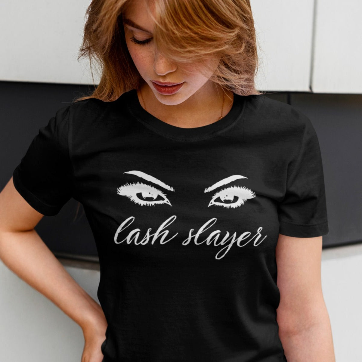 lash-slayer-black-t-shirt-womens-fashion-mockup-of-a-blonde-woman-checking-out-her-tee