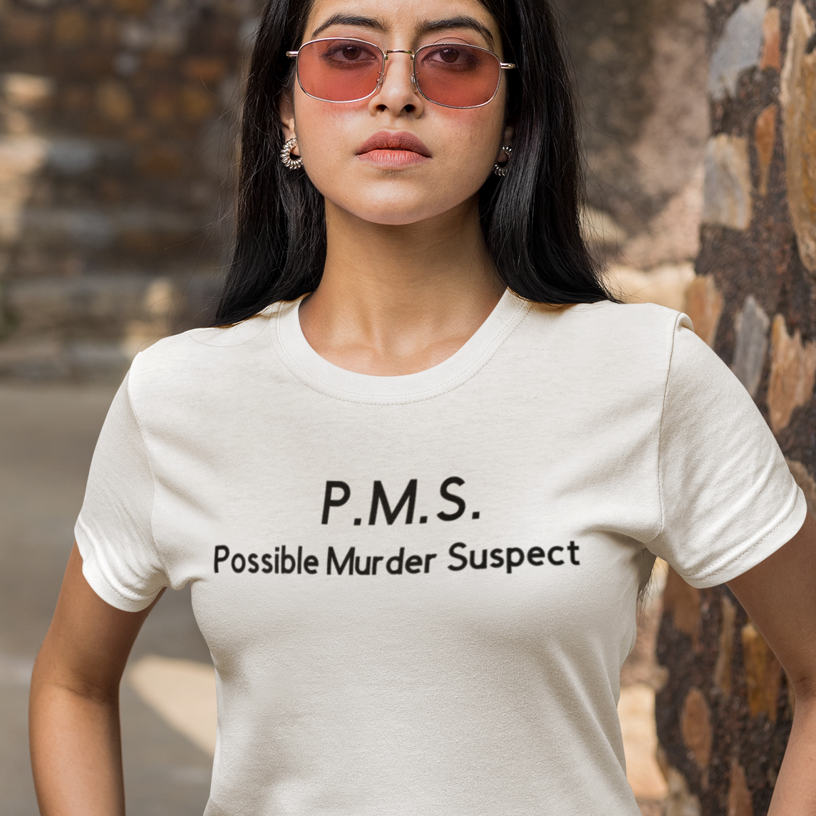 pms-possible-murder-suspect-t-shirt-mockup-featuring-a-serious-woman-with-sunglasses-with-her-hands-in-her-pockets