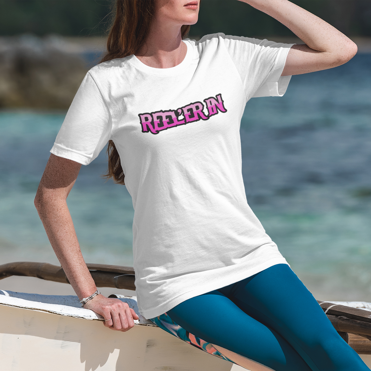 reeler-in-white-t-shirt-mockup-of-a-woman-at-the-beach-on-a-sunny-day-fishing