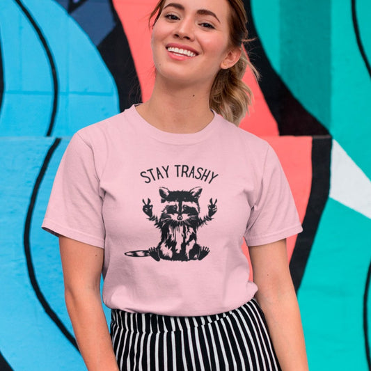 stay-trashy-with-racoon-pink-t-shirt-unisex-tee-mockup-of-a-smiling-girl-in-front-of-a-wall-with-colorful-illustrations