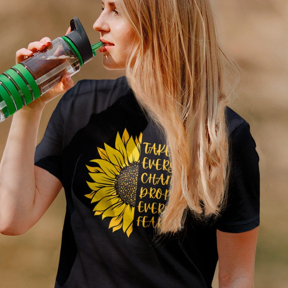 take-every-chance-drop-every-fear-black-t-shirt-sunflower-mockup-of-a-woman-wearing-a-tee-while-drinking-water-at-a-park